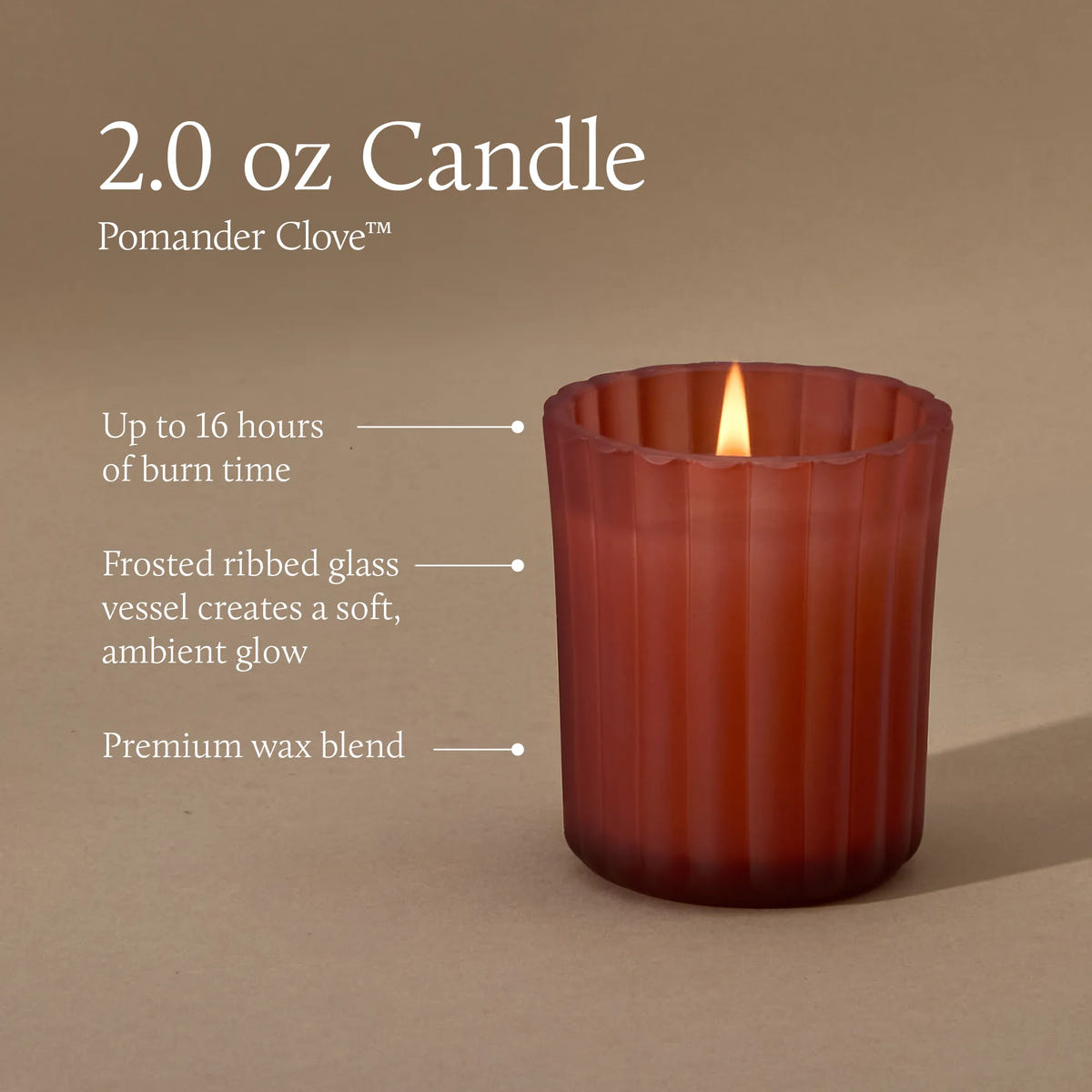 A 2.0 ounce votive candle in a frosted matte sienna orange glass vessel with a lit flame. Text indicates a burn time of up to 16 hours, a non-metal wick, reusable glass vessel, and premium wax blend.