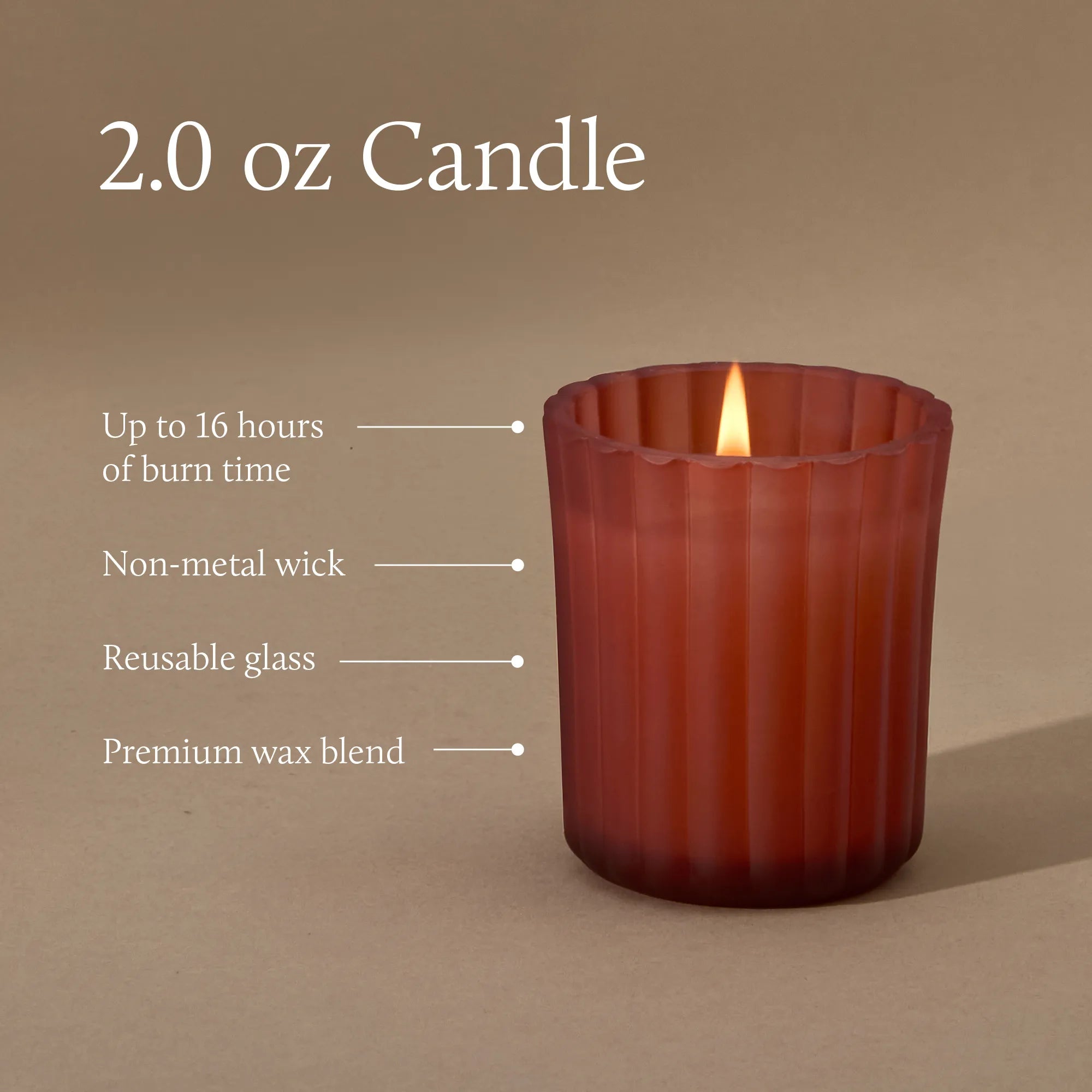 A 2.0 ounce votive candle in a frosted matte sienna orange glass vessel with a lit flame. Text indicates a burn time of up to 16 hours, a non-metal wick, reusable glass vessel, and premium wax blend.