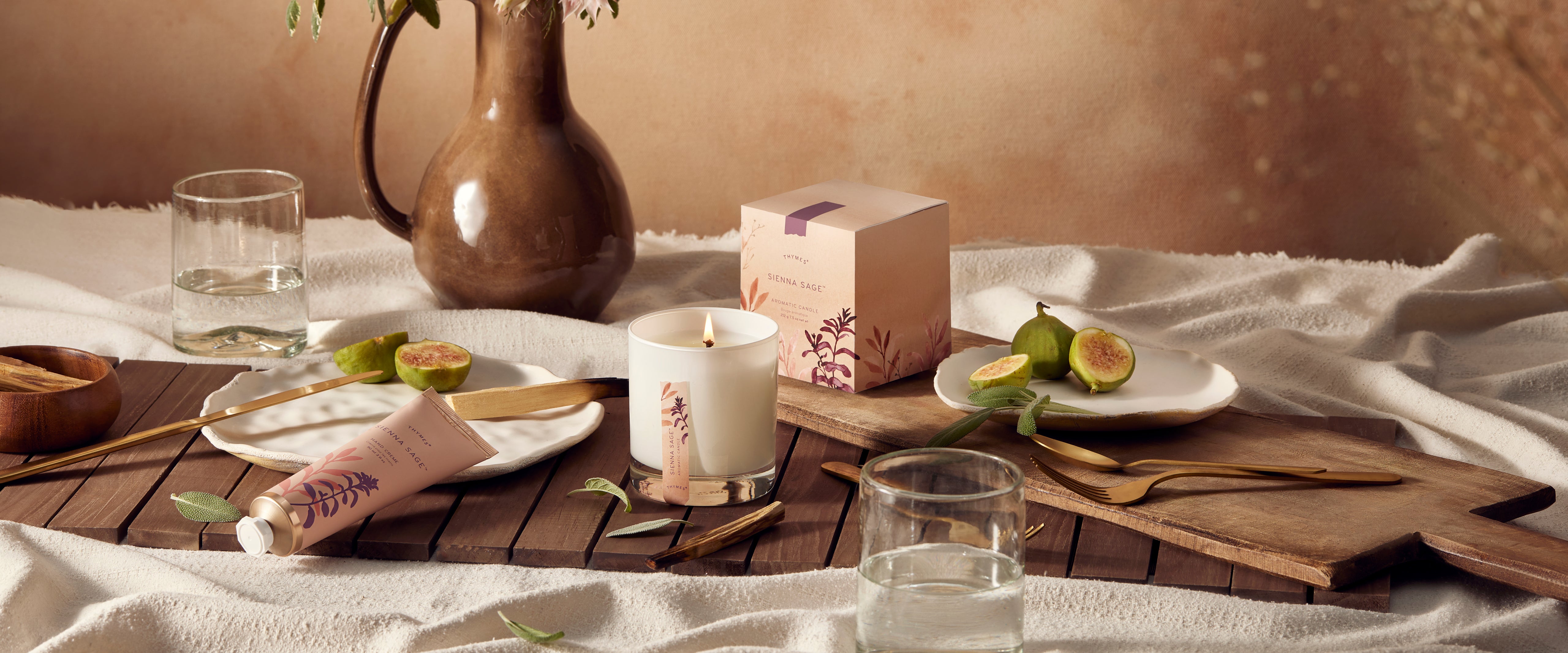 Table setting with candles, fruit, and a vase on a wooden table.